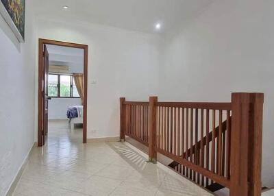 Upper hallway with wooden railing and view into bedroom