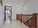 Upper hallway with wooden railing and view into bedroom