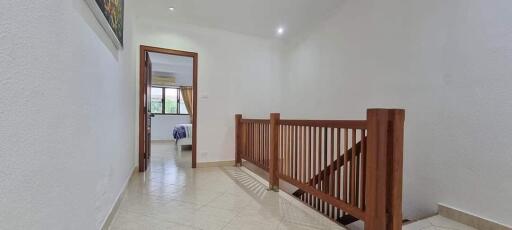 Upper hallway with wooden railing and view into bedroom