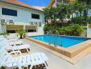 Outdoor swimming pool with lounge chairs and surrounding greenery