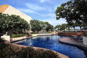 Outdoor swimming pool area with lounging chairs and greenery