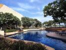 Outdoor swimming pool area with lounging chairs and greenery