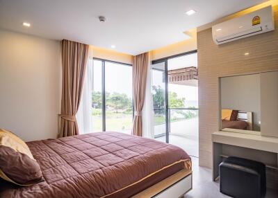 Cozy bedroom with large windows, brown bedspread, and vanity area