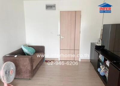 Cozy living room with brown sofa, fan, TV stand, and front door