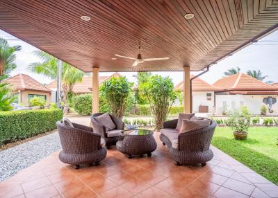 Covered outdoor patio with wicker furniture and garden view