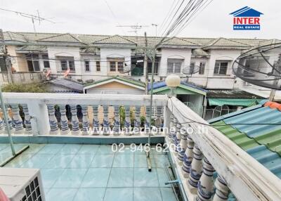 Balcony with view of nearby houses, featuring a handrail and tiles