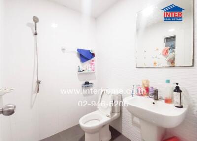 A well-lit bathroom with a toilet, sink, mirror, and a walk-in shower area.