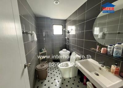 Bathroom with gray tiles, a shower area, a toilet, and a sink with a mirror