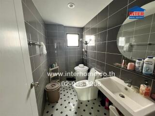 Bathroom with gray tiles, a shower area, a toilet, and a sink with a mirror