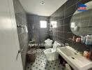 Bathroom with gray tiles, a shower area, a toilet, and a sink with a mirror