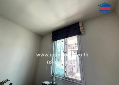 Bedroom showing a window with blinds and a book on a shelf