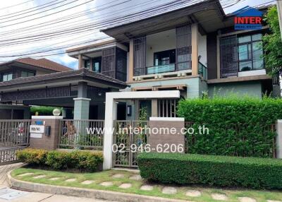 Exterior view of a modern two-story house with well-maintained garden and gate