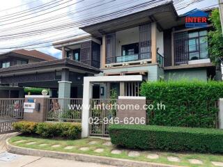 Exterior view of a modern two-story house with well-maintained garden and gate