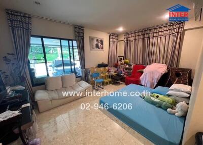 Living room with assorted furniture items and personal belongings visible.