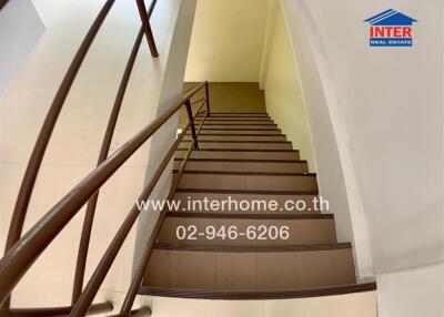 Staircase with brown railing and tiled steps