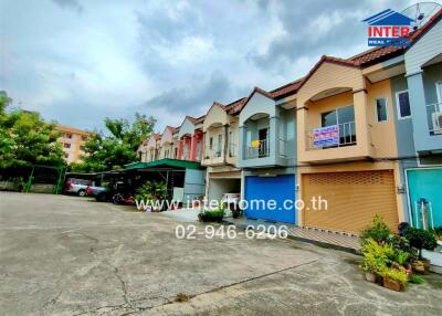 Exterior view of townhouses with parking spaces and greenery