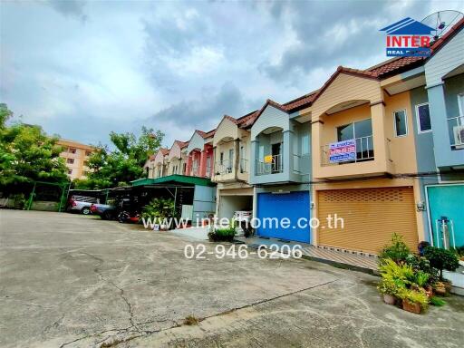 Exterior view of townhouses with parking spaces and greenery