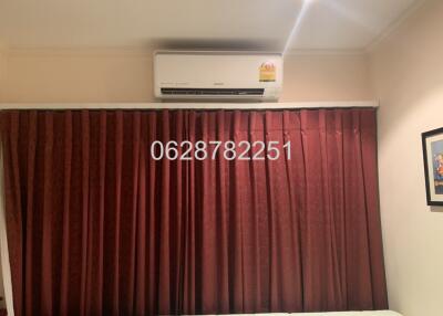 Bedroom with air conditioner and maroon curtains