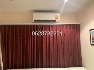 Bedroom with air conditioner and maroon curtains