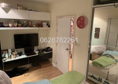 A cozy bedroom with a wall-mounted TV, large mirror, and shelves.