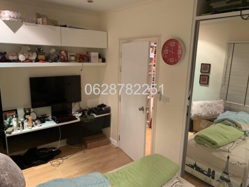 A cozy bedroom with a wall-mounted TV, large mirror, and shelves.