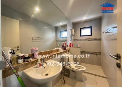 Modern bathroom with large mirror, sink, toilet, and shower area.