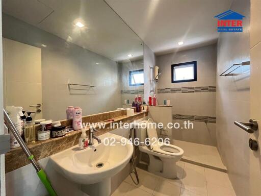 Modern bathroom with large mirror, sink, toilet, and shower area.