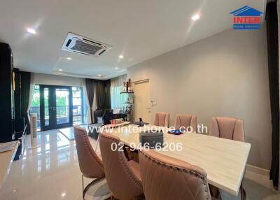 Modern dining area with a large table, chairs, and a view of the living area