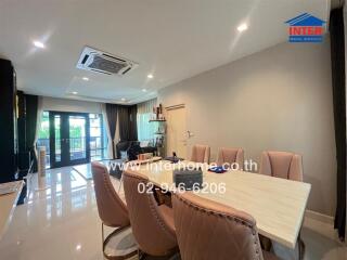 Modern dining area with a large table, chairs, and a view of the living area