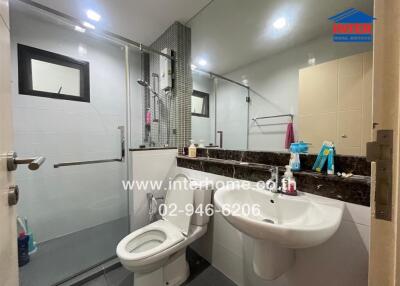 Modern bathroom with glass enclosed shower, toilet, and sink