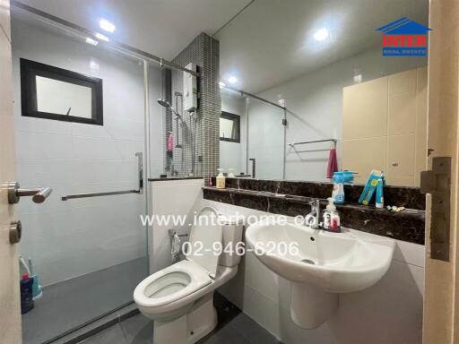 Modern bathroom with glass enclosed shower, toilet, and sink