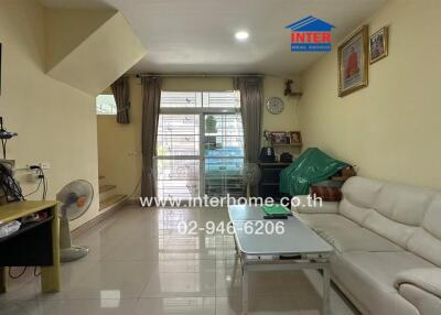 Living room with sofa, coffee table, TV, and large windows