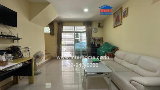 Living room with sofa, coffee table, TV, and large windows