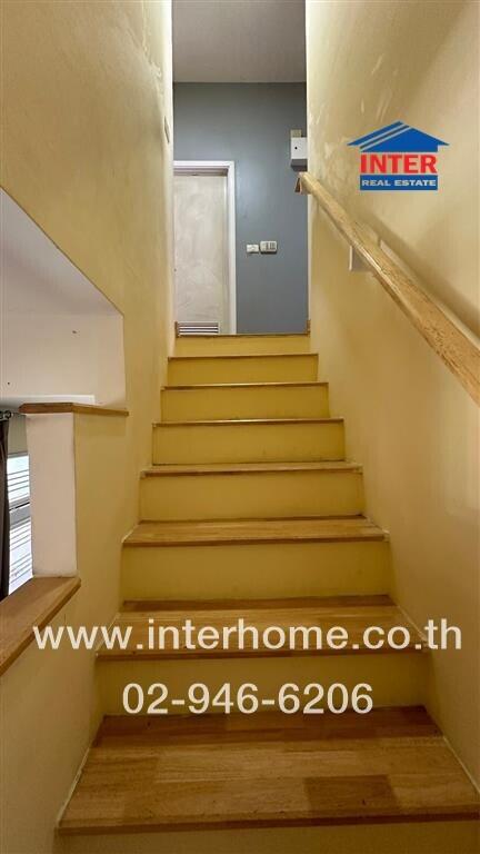 Interior staircase with yellow steps and wooden handrail