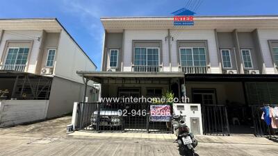 Front view of a townhouse with a covered carport and a motorcycle parked outside