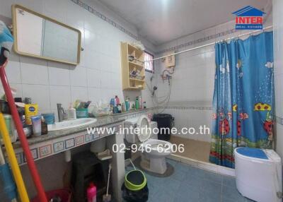 Bathroom with sink, mirror, washing machine, shower with curtain, and storage shelves