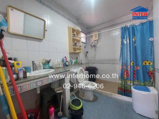 Bathroom with sink, mirror, washing machine, shower with curtain, and storage shelves