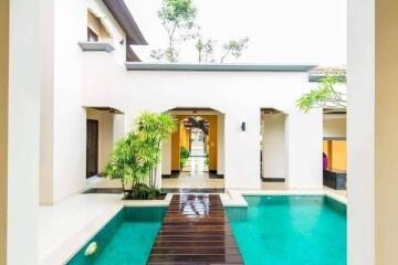 Exterior view of a modern house with a large swimming pool and wooden walkway