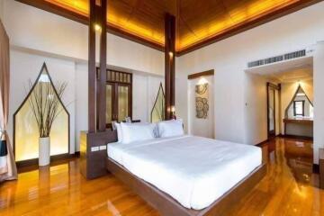 Spacious modern bedroom with wooden flooring, large bed, and contemporary decor