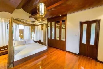 spacious bedroom with canopy bed and wooden flooring