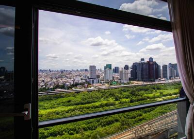 View from the living room window overlooking a cityscape and greenery