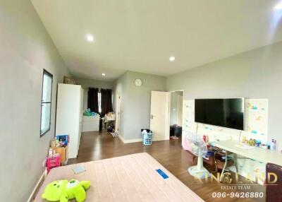 Spacious bedroom with wooden flooring, desk, TV, and decor