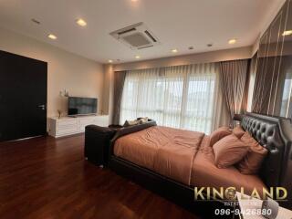 Spacious bedroom with large windows, a bed, TV unit, and wooden flooring