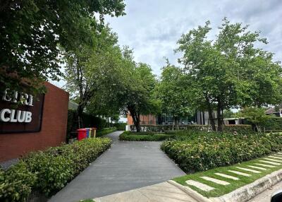 Exterior view of green landscape with pathways and signage for a club