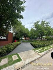 Exterior view of green landscape with pathways and signage for a club