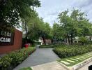 Exterior view of green landscape with pathways and signage for a club