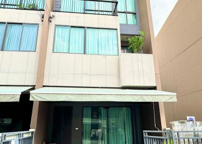 Three-story modern townhouse with large windows and balcony