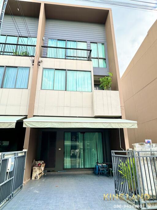 Three-story modern townhouse with large windows and balcony