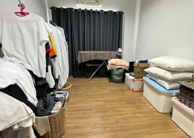 Room with hardwood floor, curtains, clothes, and storage boxes