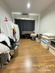 Room with hardwood floor, curtains, clothes, and storage boxes